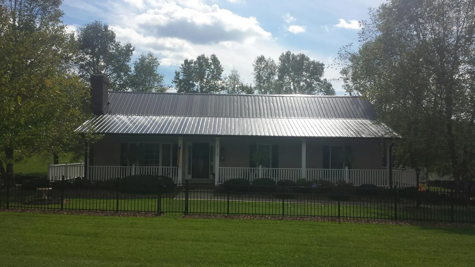 Gray metal roof on a brick ranch with a full width front porch — Gutter Guard Installation work by our crew in Oostburg