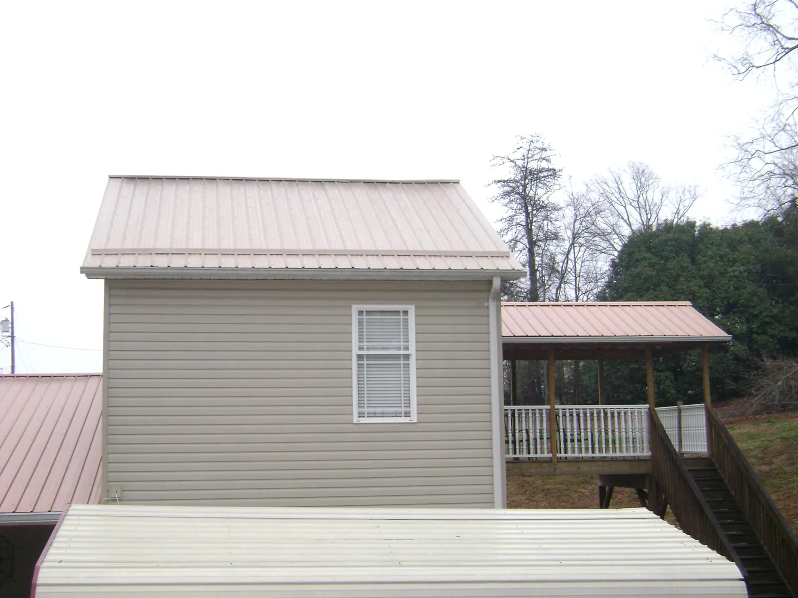 Tan metal roofs on a two story addition and attached porch, from a Roof Replacement job in Oostburg